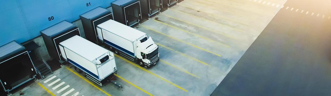 Vrachtwagens staan bij laadkades van een logistiek bedrijf.